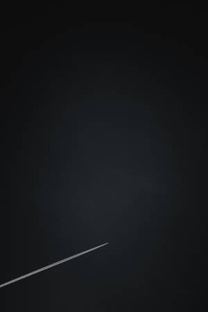 一條細小的白色飛機軌跡劃過黑暗的夜空。 — 簡約暗黑美學 壁紙