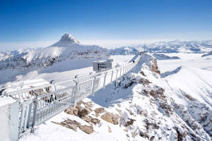 白雪覆蓋的山脊上的玻璃步道，遠方山峰，晴朗藍天。 — 塔橋 壁紙