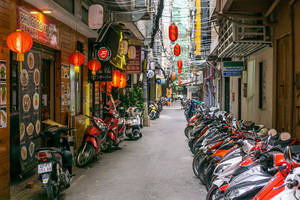 狹窄小巷，停有機車，夜間商店上方掛著紅色燈籠。 — 台北 壁紙