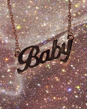 一條玫瑰金項鍊，上面有草書 'Baby' 字樣，背景是亮片。 — 小莫娜 壁紙