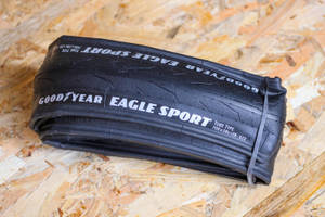 一條用橡皮筋捆綁的黑色Goodyear Eagle Sport自行車輪胎在木頭上。 — 品牌 壁紙