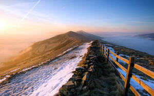 積雪的山徑、石牆和木柵欄，日出時分。 — 山脈 壁紙