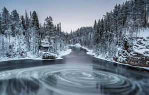 一條旋轉的河流流過被松樹環繞的雪中小屋。 — 冬季風景 壁紙