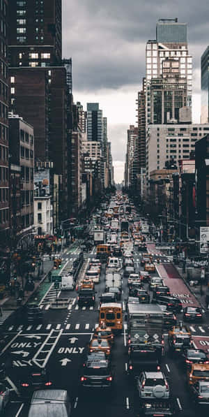 繁忙的城市街道，在多雲的天空下，充滿汽車和高樓大廈。 — 紐約 壁紙
