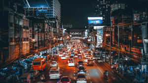 夜晚的城市街道，擠滿汽車和發光的標誌。 — 城市燈光 壁紙
