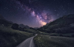 星空之夜，銀河高懸於山巒景觀之上，一條泥土小徑蜿蜒穿過草地。 — 草地 壁紙