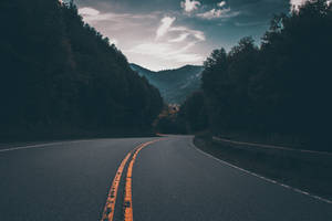暮色天空下山脈森林中的蜿蜒道路 — 卡車 壁紙