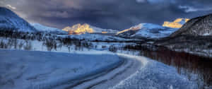 積雪的山路在暮色中蜿蜒穿過山谷。 — 冬季風景 壁紙