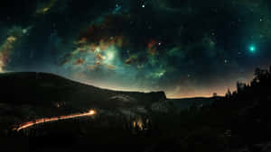 一條發光的道路蜿蜒穿過黑暗的山脈，在充滿活力的星空下，有星雲和一顆彗星。 — 風景 壁紙