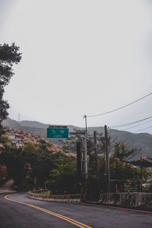蜿蜒道路穿過霧氣瀰漫的山村，帶有綠色 Jiafen 標誌