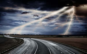 在暴風雨的天空下，一條彎曲的高速公路，明亮的閃電照亮了雲層和田野。 — 閃電麥坤 壁紙