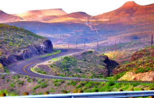 日落時分彎曲的沙漠高速公路，背景有山脈 — 德克薩斯州旗 壁紙