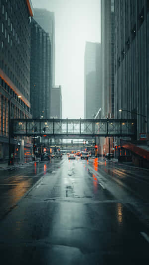雨中的城市街道，高樓大廈和閃爍的交通燈在濕漉漉的路面上反射。 — iPhone Xs Max 壁紙