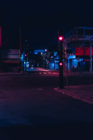 夜晚中一條安靜的城市街道，被紅色和藍色的霓虹燈招牌和交通燈照亮。