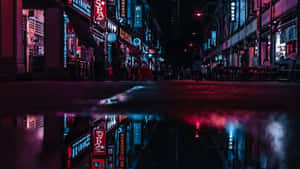 霓虹燈在夜晚繁忙的城市街道上的雨水坑中反射。