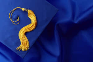 藍色帽子和布料上的金色畢業流蘇特寫。 — 畢業 壁紙