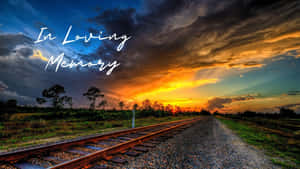 通往日落天空的鐵路軌道，文字為 In Loving Memory — 日落 壁紙