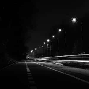 夜晚道路，有路燈和模糊的汽車運動軌跡。 — iPad 第10代 壁紙