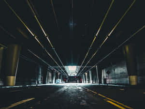 長長的黑暗隧道，有黃色管道和柱子，通往明亮的出口，有汽車和紅燈。 — 洞穴 壁紙