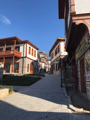 鵝卵石街道兩旁排列著傳統石頭和木造建築，上方是清澈的藍天。 — 安卡拉 壁紙