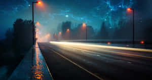 夜晚一條潮濕空曠的道路，有發光的街燈和星光藍色天空。 — 高解析度桌面 壁紙