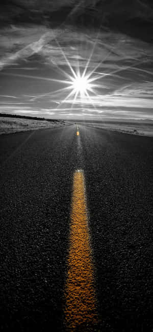 在明亮太陽下的一條長直道路，帶有黃色中心線。 — iPhone 17 Pro 壁紙