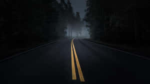 夜間黑暗的森林道路，黃色中心線消失在霧中。 — 夜晚 壁紙