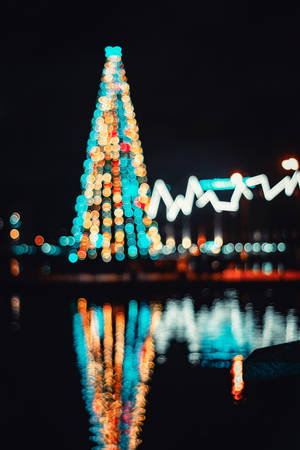 夜晚水中倒映的聖誕樹散景燈光。 — 聖誕燈飾 壁紙