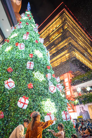 人群在夜晚的城市中享受飄雪下的節日聖誕樹。 — 聖誕樹動畫 壁紙