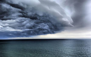 戲劇性的暴風雲懸浮在平靜的海洋地平線上。 — 海洋 壁紙