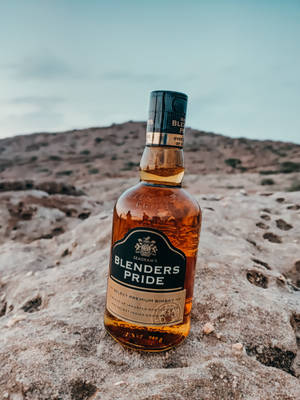 Blenders Pride 威士忌酒瓶在沙漠岩石上，暮色中 — 海灘 壁紙