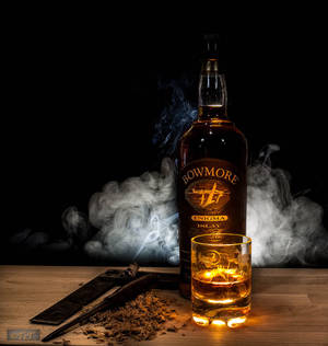 Bowmore 威士忌瓶和酒杯，帶有煙霧和雪茄剪在木桌上。 — Galaxy Z Flip7 FE 壁紙