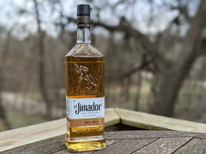 戶外木桌上的一瓶 el Jimador 龍舌蘭酒 añejo。 — 品牌 壁紙