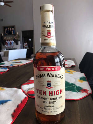 一瓶Hiram Walker's Ten High波本威士忌放在有節日餐墊的木桌上。 — 麥迪遜·比爾 壁紙