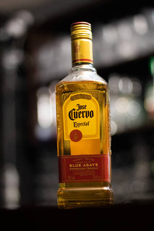 一瓶Jose Cuervo龍舌蘭酒放在酒吧上，背景有模糊的燈光。 — 小米平板 壁紙