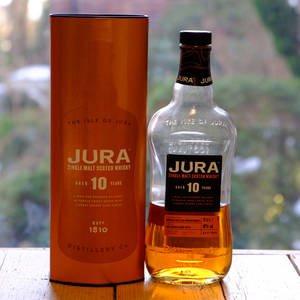 Jura 10年威士忌酒瓶和盒子放在窗邊的木桌上。 — 動態圖 壁紙