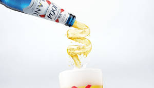 一瓶Kronenbourg 1664啤酒將金色液體倒入帶有泡沫的玻璃杯中。 — 啤酒 壁紙