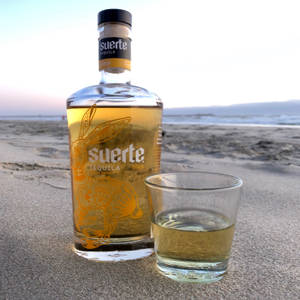 Suerte龍舌蘭酒瓶和玻璃杯在沙灘日落 — 海灘 壁紙