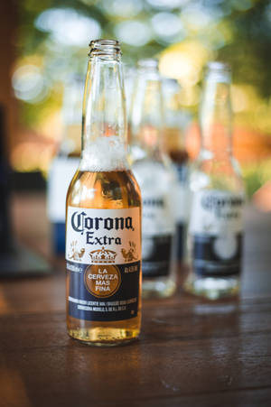 戶外木桌上的一瓶冰涼Corona Extra啤酒瓶。 — 麥迪遜·比爾 壁紙
