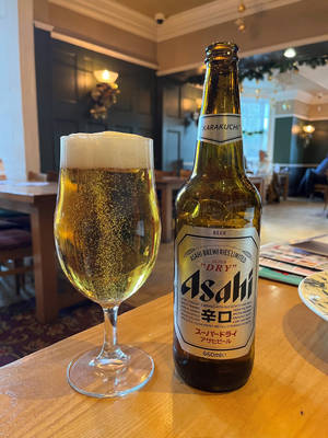 酒吧木桌上的一瓶朝日啤酒和一杯啤酒。 — 啤酒 壁紙