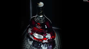 在聚光燈下，紋理表面上閃爍著水晶裝飾的Hennessy XO酒瓶。 — 省電 壁紙
