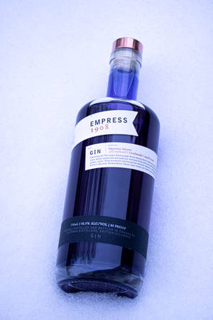 一瓶標有Empress 1908的深藍色琴酒瓶，在藍光下放置在雪地上。 — Huawei MatePad 11.5 S (2025) 壁紙