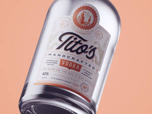 Tito's Handcrafted Vodka酒瓶，標籤細節在蜜桃色背景上 — 標誌 壁紙
