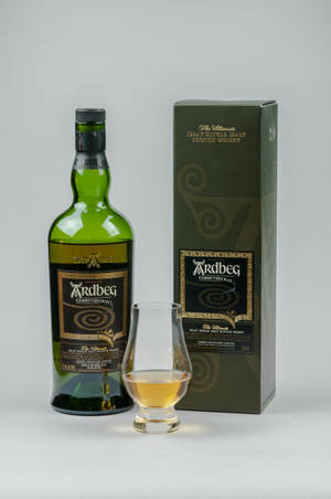 白色背景上的綠色 Ardbeg 威士忌酒瓶、盒子和品酒杯。 — Huawei MatePad 12 X (2025) 壁紙