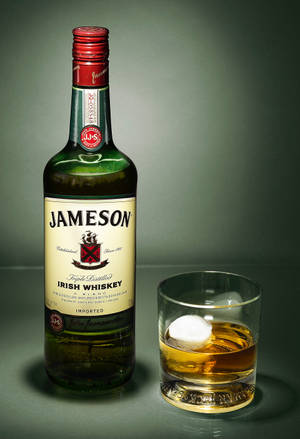 Jameson愛爾蘭威士忌酒瓶和杯子，杯中有冰塊，放在灰色表面上。 — 小米平板 7 Ultra 壁紙