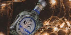 一瓶被發光串燈環繞的 Casa Noble 龍舌蘭酒。 — 聖誕燈飾 壁紙