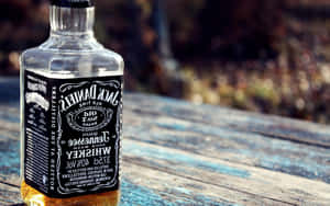 戶外藍色木桌上的一瓶Jack Daniel's威士忌。 — 16:10 壁紙