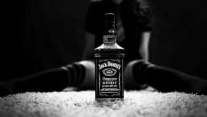 地毯上的一瓶 Jack Daniel's 威士忌，後面有一個模糊的人影。 — 葡萄酒 壁紙