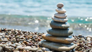 卵石海灘上堆疊的石頭，伴隨著海浪 — 森林景觀 壁紙