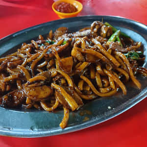 金屬盤上的炒麵配肉和青菜。 — 1:1 壁紙
